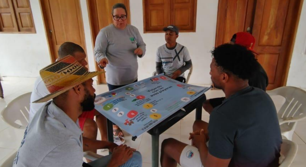 Participantes locales interactúan con el juego “Ruta de supervivencia de las aves playeras”, una herramienta educativa que promueve el aprendizaje sobre los desafíos que enfrentan estas especies durante su migración y la importancia de su conservación en el Golfo de Tribugá.